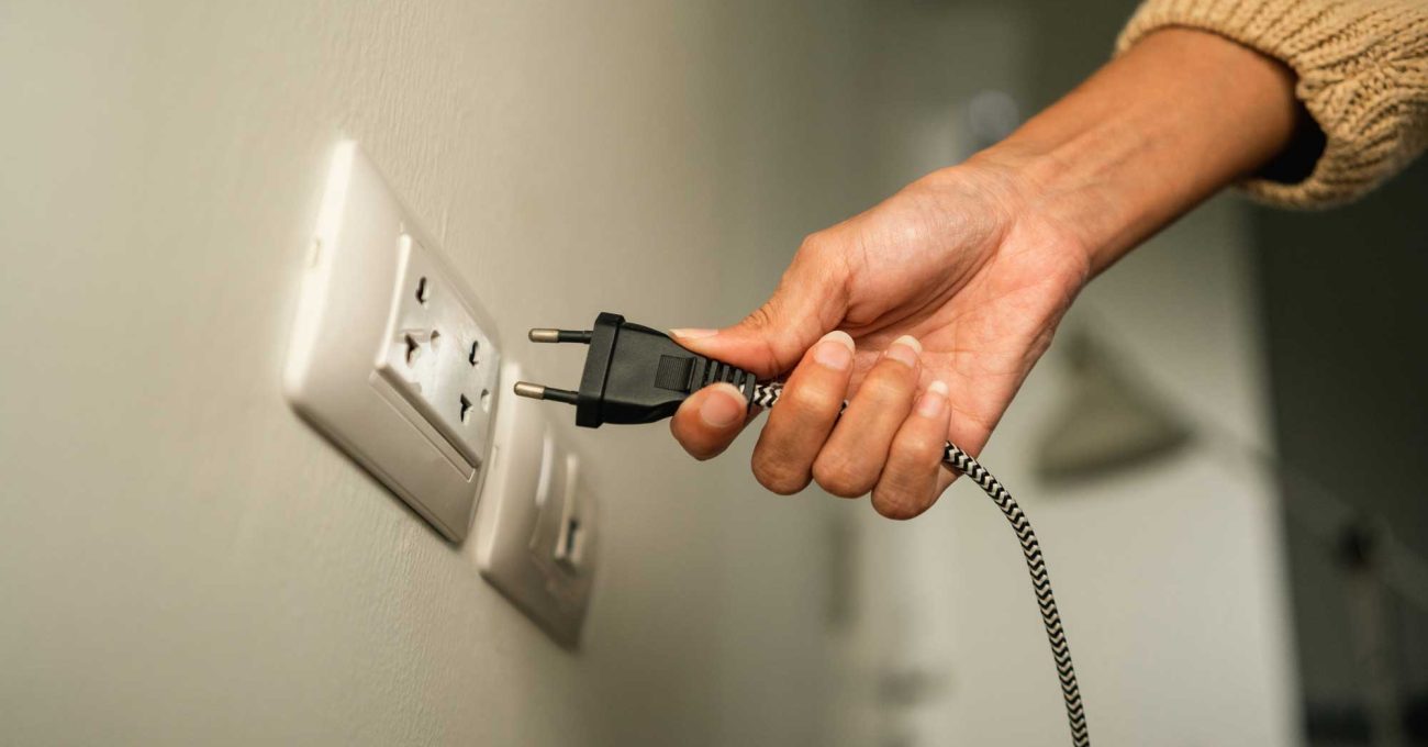 a hand plugging in an electrical cord