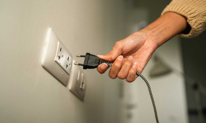 a hand plugging in an electrical cord